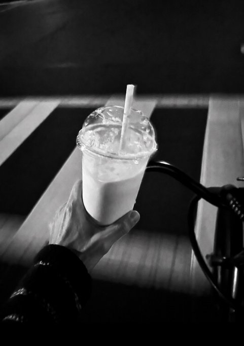 A hand holds a plastic cup with a domed lid, straw, and iced milky drink over what appears to be a road with crosswalk lines and a bicycle, rendered in moody black and white.

Note on context: The phrase "never kys" is commonly used in online slang as a direct reference to the suicide helpline number "988" or as an acronym meaning "kill yourself." When paired with an image like this—someone casually holding a drink in an everyday urban setting—it creates a jarring juxtaposition between mundane, lived moments and references to crisis or self-harm. If you or someone you know is struggling, please reach out to the 988 Suicide & Crisis Lifeline (call or text 988 in the US) or a local crisis resource.