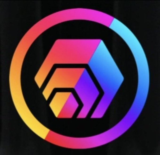 A colorful gradient logo featuring a geometric cube design in pink, orange, purple, and blue tones enclosed within a circular ring, displayed against a dark background.