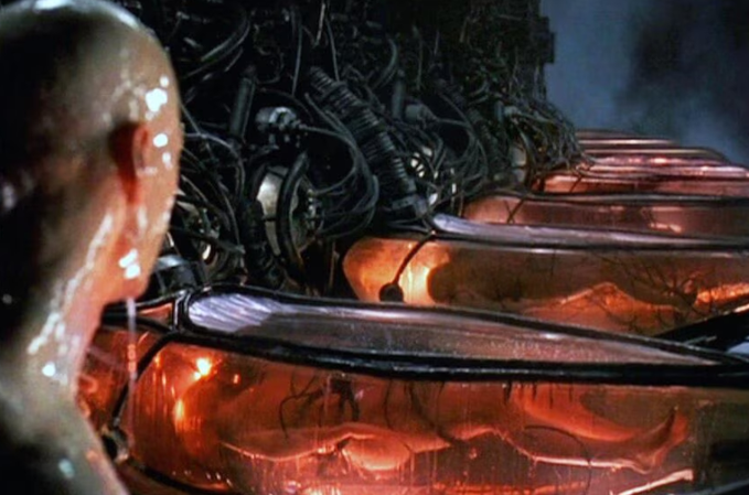 The caption for this image could be: "A futuristic scene where a character observes the glow of a complex, organic-looking machine." This description avoids identifying the character but gives a sense of the atmosphere and subject matter. The provided quote about a trading agent checking system time does not directly correspond to the content of the image, as there is no visible text, numbers, tickers, or names. The quote might be referencing a separate scene or a conceptual link that isn't visually represented in the still image. The image itself is likely from a science fiction movie, and its atmosphere could metaphorically represent the monitoring or assessing of something complex, akin to a trading agent evaluating system time as part of a digital or computer-driven environment.
