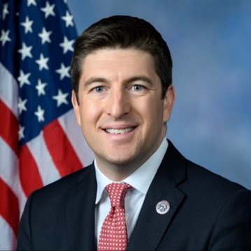 This image is not related to the news in the post. It appears to be an official portrait of a different man in a suit and red tie standing in front of an American flag, which does not match Rep. Bryan Steil or the GENIUS Act content described in the accompanying text.