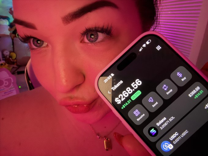 A close-up of a person holding a smartphone displaying a portfolio app showing '$268.56' in tokens with a green '+14.51' gain, including holdings in Solana (3.00671 SOL) and USDC.