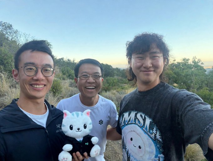 Three smiling men pose for a selfie on a hillside at dusk, with one holding a plush cat, as they celebrate a "10x longed HYPE" win.