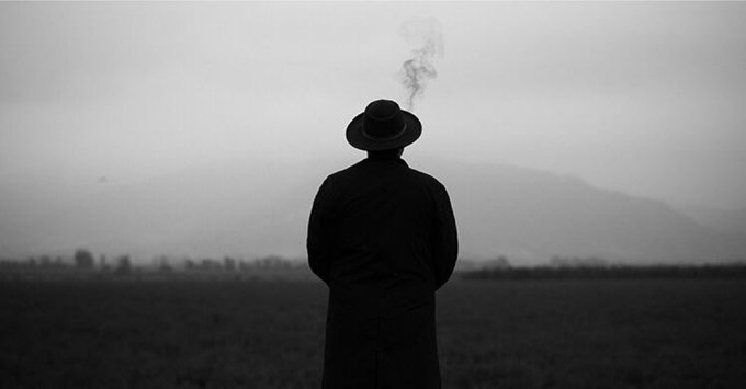 A solitary figure in a wide-brimmed hat stands silhouetted in a misty field, smoke rising from above. The image's contemplative, introspective mood pairs with the post's crypto giveaway, reinforcing a "solitary reflection before fortune" theme as the poster picks winners and asks for $SOL addresses.