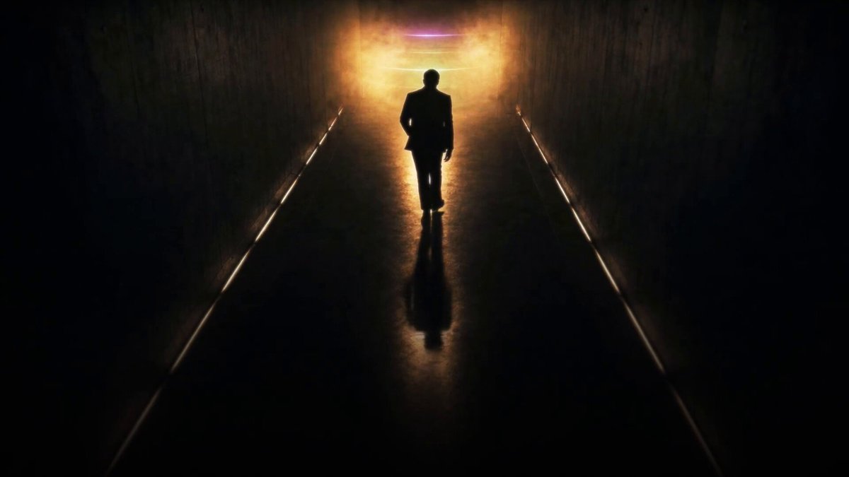 The image shows a man walking down an empty hallway, with his shadow visible on the floor as he moves towards the right side of the frame. The hallway appears to be illuminated by a bright light source coming from the left side, creating a contrast between the darkness and the light. In the background, there is a text that reads "All that glitters is coming to Solana." This phrase seems to be related to the image's theme or context, possibly referring to the man's journey through the tunnel or the idea of finding something valuable in an otherwise dark environment.