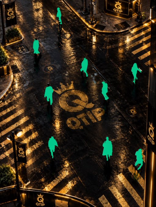 A dramatic nighttime street scene with wet pavement, featuring the QTIP logo and several glowing green silhouettes of people walking across a crosswalk.