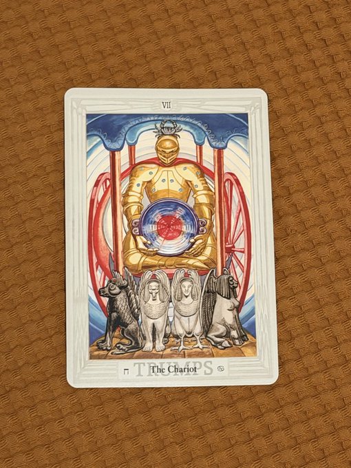 A tarot card numbered 'VII' titled 'THE CHARIOT' depicts a golden armored figure holding a red orb, standing between four sphinx-like creatures in black, gray, white, and brown.