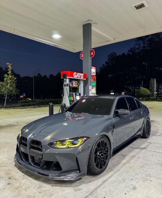 A modified gray BMW sedan with neon yellow accents is parked at a gas pump marked “GATE,” with red fuel-price signs showing “3” and “4.” The post invites users to drop their “$SOL” addresses, but the image contains no visible Solana address or ticker.
