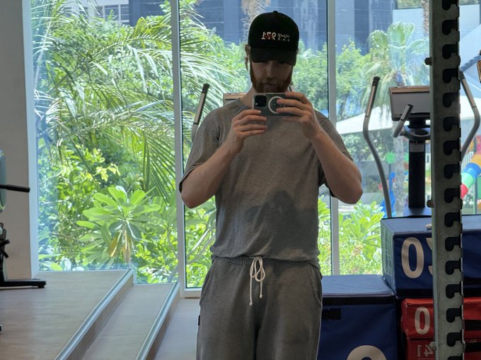 The image features a man taking a selfie with his cell phone, likely capturing his workout progress at the gym. The man is wearing a gray shirt and sweatpants while holding up his phone for the picture. In the background, there are several exercise machines that suggest he has been working out in this space. The caption to the image reads "i don't need a spotter @monad doesn't need a stop loss easily the fittest chain". This implies that the man is determined and focused on his fitness goals without any assistance from others during his workout sessions.

The gym equipment includes various types of machines, such as treadmills, weightlifting benches, and exercise bikes. The presence of these machines indicates that this location caters to different types of workouts for its members.