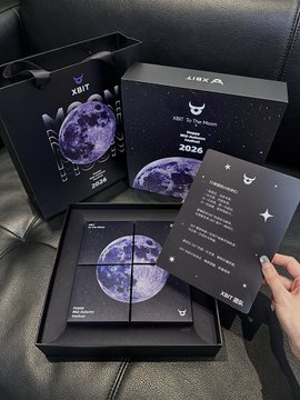An unboxing photo showing a '2026 To the Moon' lunar-themed merchandise set with boxes, cards, and stickers, displayed on a black leather surface.