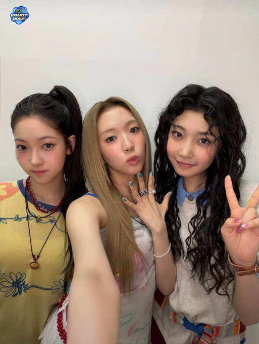 Three young women pose together in a selfie-style photo, with a 'M COUNTDOWN' logo visible in the upper left corner.