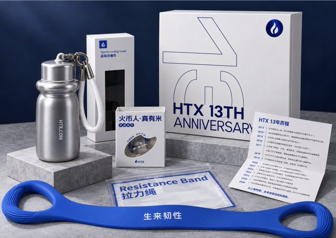 A promotional display of the HTX 13th Anniversary gift box, featuring a stainless steel "HTX.COM" sports cooling towel water bottle, a "Resistance Band" (拉力绳) with "生来韧性" printed on it, a pin badge, and an anniversary card listing the platform's milestones from 2013 onward. The setup highlights the commemorative merchandise referenced in the post celebrating HTX's 13 years in the crypto space.