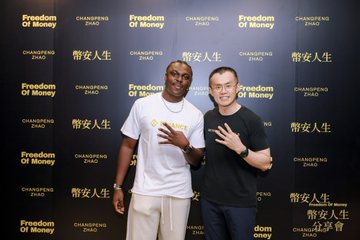 Two men pose in front of a backdrop reading "Freedom Of Money" and "CHANGEMAKERS ZHAO," with the post suggesting this was taken at a book signing event in Hong Kong featuring Binance founder CZ (Changpeng Zhao).