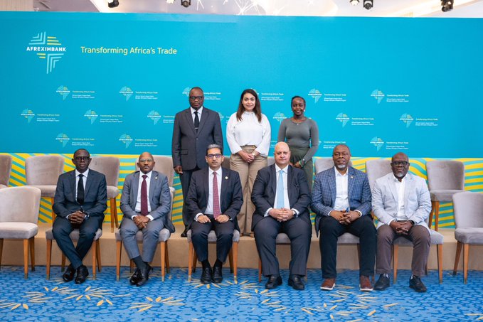 Group photo of attendees at the Afreximbank "Transforming Africa's Trade" event, with four seated officials and three people standing behind them against a blue backdrop.