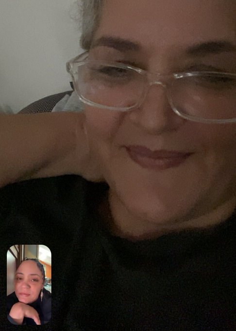 A selfie of a smiling woman wearing glasses in a video call, with a smaller picture-in-picture view of another young woman in the corner.
