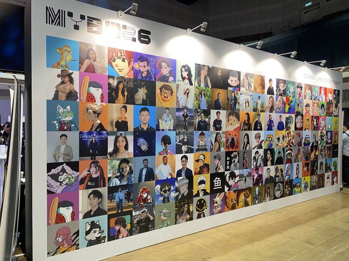 An exhibition display board labeled 'MITOSIS' featuring a large grid of diverse character portraits and illustrations, likely at a content creator convention.