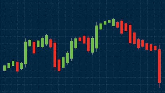 A candlestick chart on a dark background shows a price progression that rises steadily with mostly green candles before peaking and reversing into a series of red candles that drop sharply. The image illustrates the psychological effect of seeing red bearish candles, reinforcing the post's point that the color red is subconsciously linked to danger and can negatively impact a trader's mindset.