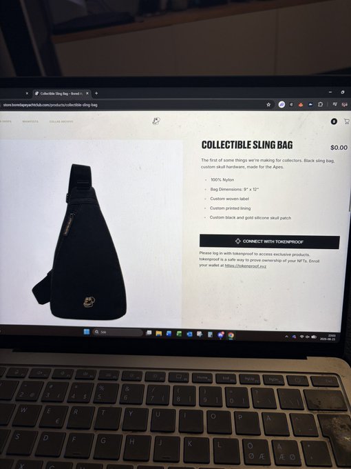 Photograph of a laptop screen showing a 'COLLECTIBLE SLING BAG' product page from tokenproof, describing a 100% nylon, custom skull hardware bag with dimensions of 9" x 12".