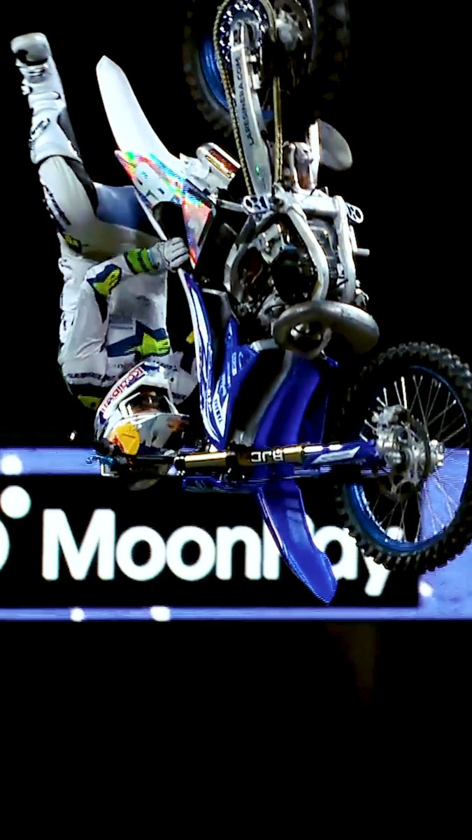 A motocross rider performs a trick in front of a "Moonpay" logo, likely representing one of the winners of the Never Been Done Award. The rider's helmet displays a Red Bull logo, a prominent sponsor in extreme sports.