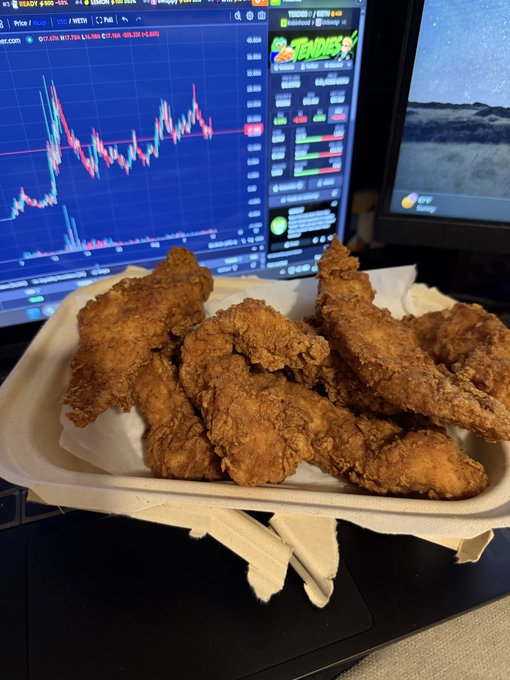 A compostable tray piled high with crispy fried chicken tenders sits in front of trading monitors displaying live charts and a colorful "TENDIES" logo, humorously pairing the homophone of stock gains ("tendies") with the meal as part of the daily $TENDIES posting streak.