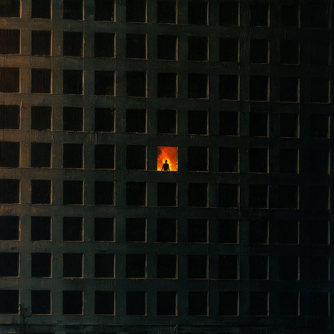 A lone silhouetted figure stands in a single illuminated window of an otherwise dark, grid-like building façade, embodying quiet solitude amid the stillness of night.