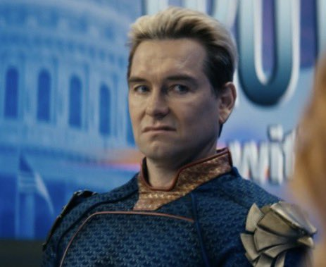 A photo of actor Antony Starr, who plays the character Homelander from the TV series 'The Boys,' wearing his blue and gold superhero costume with a serious expression.
