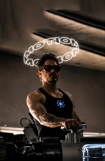 A muscular man wearing red sunglasses and a black tank top with a glowing blue chest piece, standing beneath a neon sign that reads 'MOTION MOTION' in a stylized font.