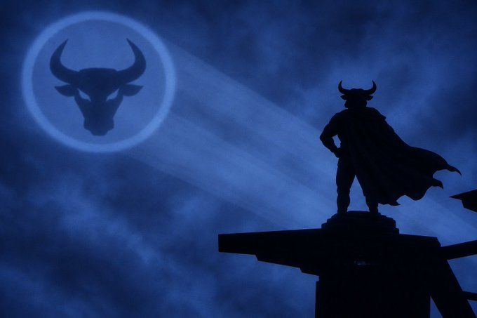 A dramatic silhouette of a caped figure with horns standing on a structure against a dark blue cloudy sky, with a Chicago Bulls logo appearing like a moon in the background.