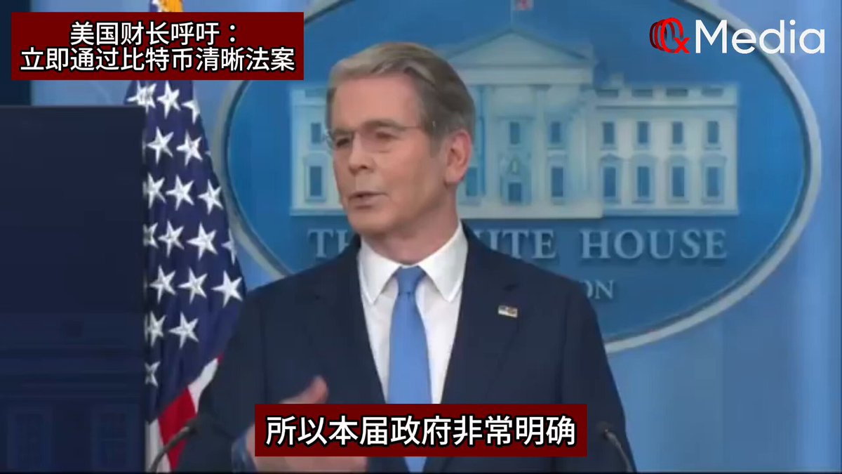 The image shows a man giving a speech, with his face clearly visible as he speaks into a microphone. The setting appears to be an official event or gathering, possibly related to the White House. The man's attire consists of a suit and tie, suggesting that this is a formal occasion. The background features a large American flag, indicating that the event may have some connection to the United States.