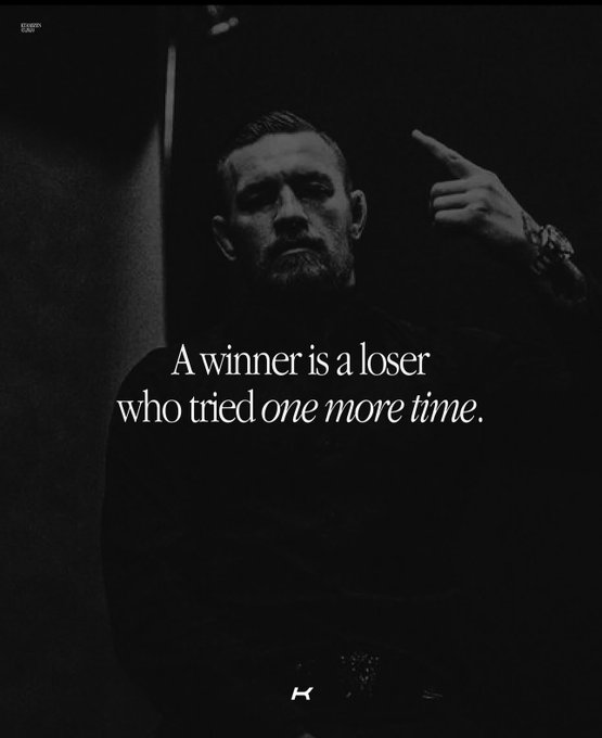 A dark, moody motivational image featuring a man with a beard pointing upward, with the text "A winner is a loser who tried one more time."