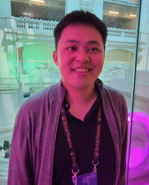 The image features a man wearing a gray cardigan standing next to a glass window. He is smiling at the camera while holding up his wallet or purse, which has an ID tag showing he's a cryptocurrency enthusiast. The caption for this image reads "CRYPTO BILLIONAIRE DOUBLES DOWN ON BITCOIN, REJECTS $250K ETH DFG founder James Wo, who turned a $20 million family investment into a billion-dollar crypto fund, says market data does not support Tom Lee's $250,000 Ethereum target. His conviction remains firmly with $BTC." The man is also wearing an ID tag that reads "Xtremely Confident Cryptocurrency Investor Xtremely Confident."