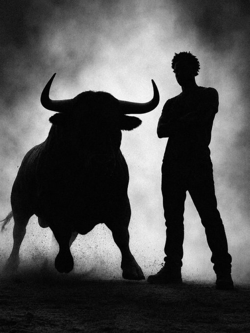 A black and white silhouette image showing a large bull with prominent horns standing next to a person with crossed arms against a hazy background.