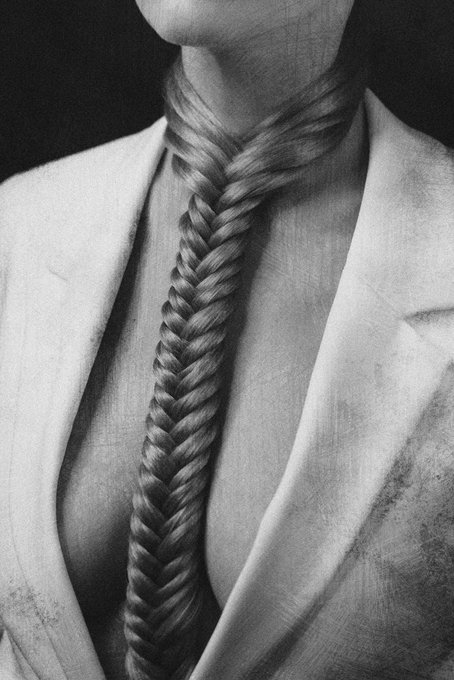 A black and white illustration of a person wearing a suit and tie, where the tie is made of a long braided fishtail plait of hair extending from the neck.