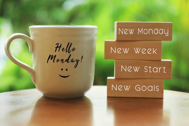 A motivational Monday-themed image features a white mug reading 'Hello Monday!' beside stacked wooden blocks labeled 'New Monday', 'New Week', 'New Start', and 'New Goals'.