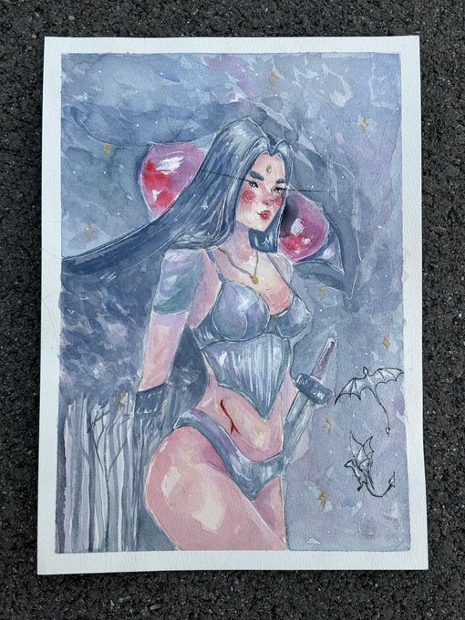 A watercolor painting shows a dark-haired woman with a bindi in a blue corset and lingerie, set against a starry purple background with small bat sketches.