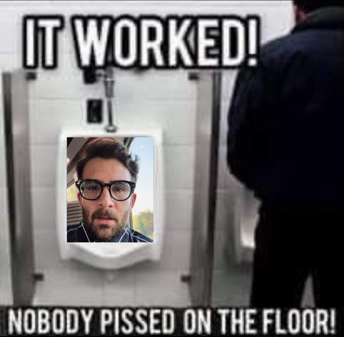 The image features a man with glasses taking a picture of himself using his phone, which has a photo of him standing next to a urinal. The caption reads "It worked! Nobody Pissed on the floor!" This humorous statement suggests that the man is making fun of someone who has accidentally pooped in the urinal.