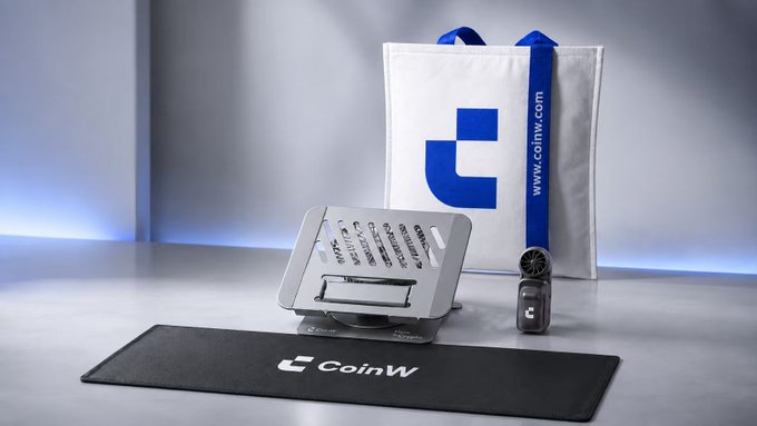 A gray stand displaying "CoinW" branding sits next to a smartwatch and a black "CoinW" desk mat, with a white shopping bag featuring the blue CoinW logo and "www.coinw.com" URL in the background. The promotional merchandise shown ties directly to the post, which thanks CoinW for sending branded gear to keep the user comfortable during gym workouts.