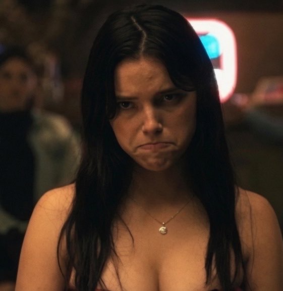 The image features a woman with long dark hair wearing a necklace, making her look pretty or attractive. She has a serious expression on her face as she looks at something off-camera. The caption of the image reads "Mfs when Claude hacks their wallets". This phrase is likely an inside joke or reference to a recent event involving someone named Claude who was known for being a con artist and stealing people's wallets.