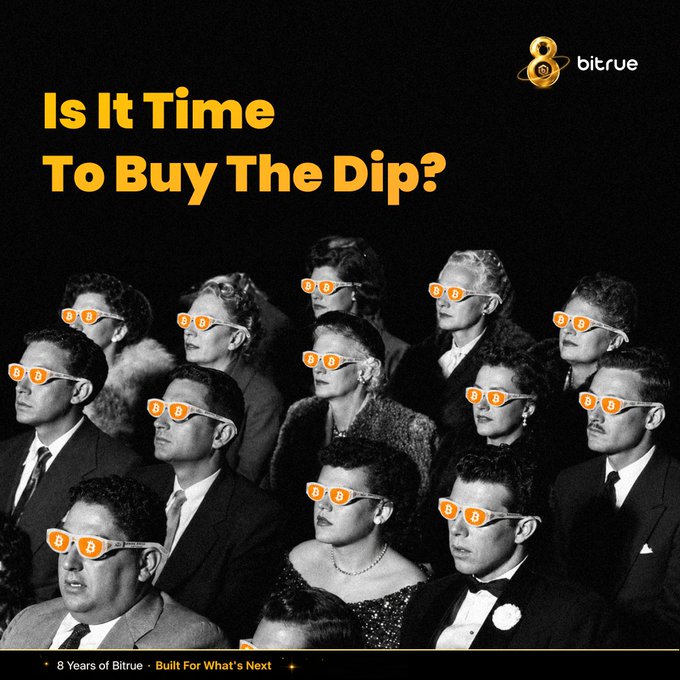 The image is a Bitrue promotional graphic featuring a vintage black-and-white photo of a crowd wearing orange "B" logo sunglasses, with the headline "Is It Time To Buy The Dip?" in bold orange text. The Bitrue logo appears in the top right corner, and the bottom text reads "8 Years of Bitrue • Built For What's Next," reinforcing the post's message about using the Bitcoin dip as a buying opportunity on the Bitrue exchange.