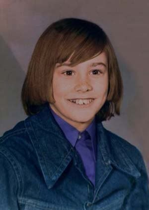 A vintage portrait of a smiling young girl with a brown bob haircut, wearing a purple shirt under a denim jacket.