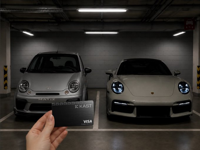 The image shows a person holding up two different cars, one silver and one black, both of which are parked in a garage or parking lot. The silver car has a Visa card attached to its windshield, while the black car also has a Visa card on its windshield. The person is standing next to these vehicles, possibly discussing their features or admiring them.
