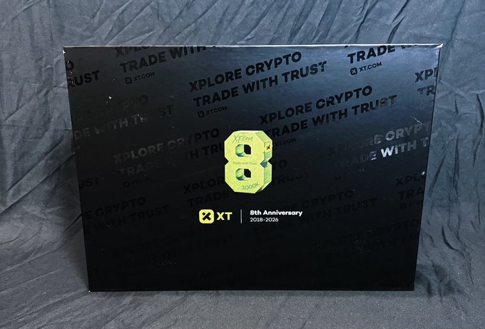 The image shows a black gift box with "XPLORE CRYPTO TRADE WITH TRUST" text and an XT.com logo celebrating the exchange's 8th anniversary (2018-2026), featuring a gold "8" emblem in the center. This relates to the post celebrating XT.com's 8th anniversary, where the user received promotional merchandise including an ROG keyboard valued at 999 yuan as a gift for the milestone occasion.