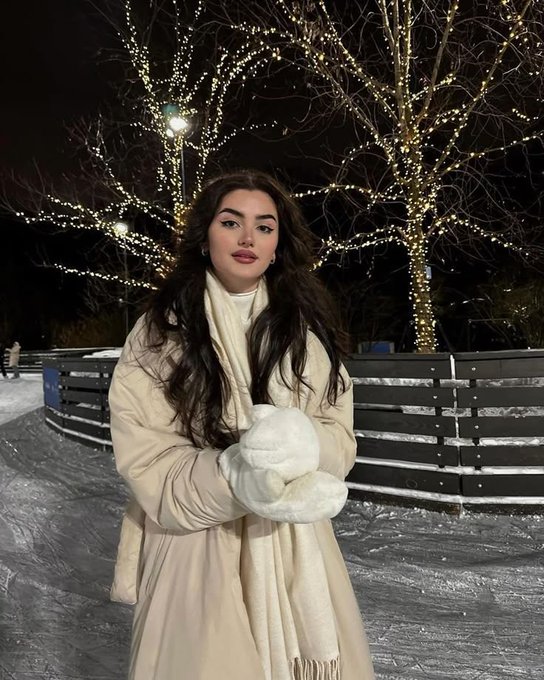 The image features a woman standing alone in the snow wearing a white jacket and scarf. She is holding her hands up in front of her chest as if posing for a photo, possibly at an indoor event or during a winter gathering. The setting appears to be indoors with artificial lights providing illumination. The post suggests that people should stay active by participating in sports activities like Base and Polymarket to build their onchain footprint consistently throughout the year. It also emphasizes the importance of maintaining a healthy lifestyle while focusing on smart choices and staying consistent, regardless of the weather conditions outside.