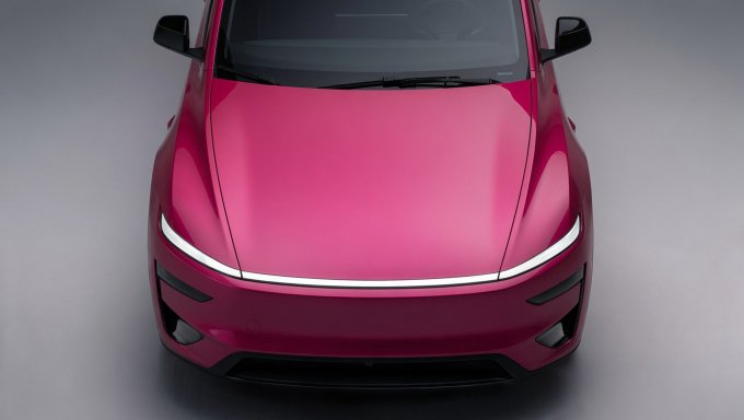 A front-facing, high-angle view of a sleek, bright pink sports car or concept vehicle featuring a continuous horizontal LED light bar across the front.