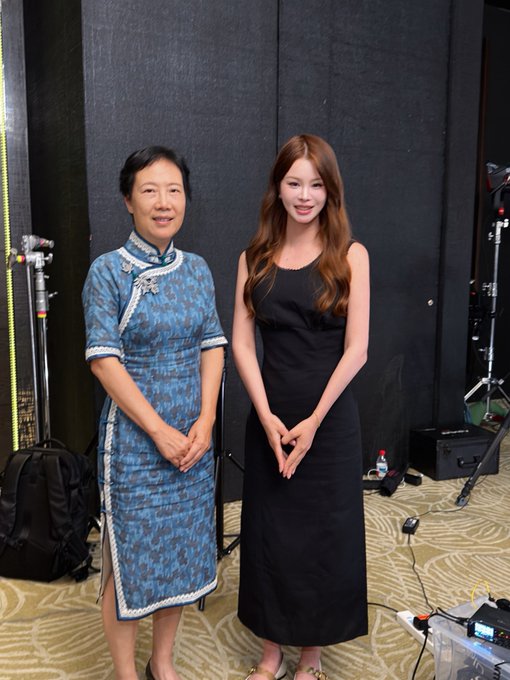 A photo of two women standing together at the "Binance Reception Room" (币安会客厅), featuring financial commentator Ye Tan (叶檀) in a traditional blue qipao alongside a younger woman in a black dress, posing in what appears to be a studio setting with filming equipment visible in the background.