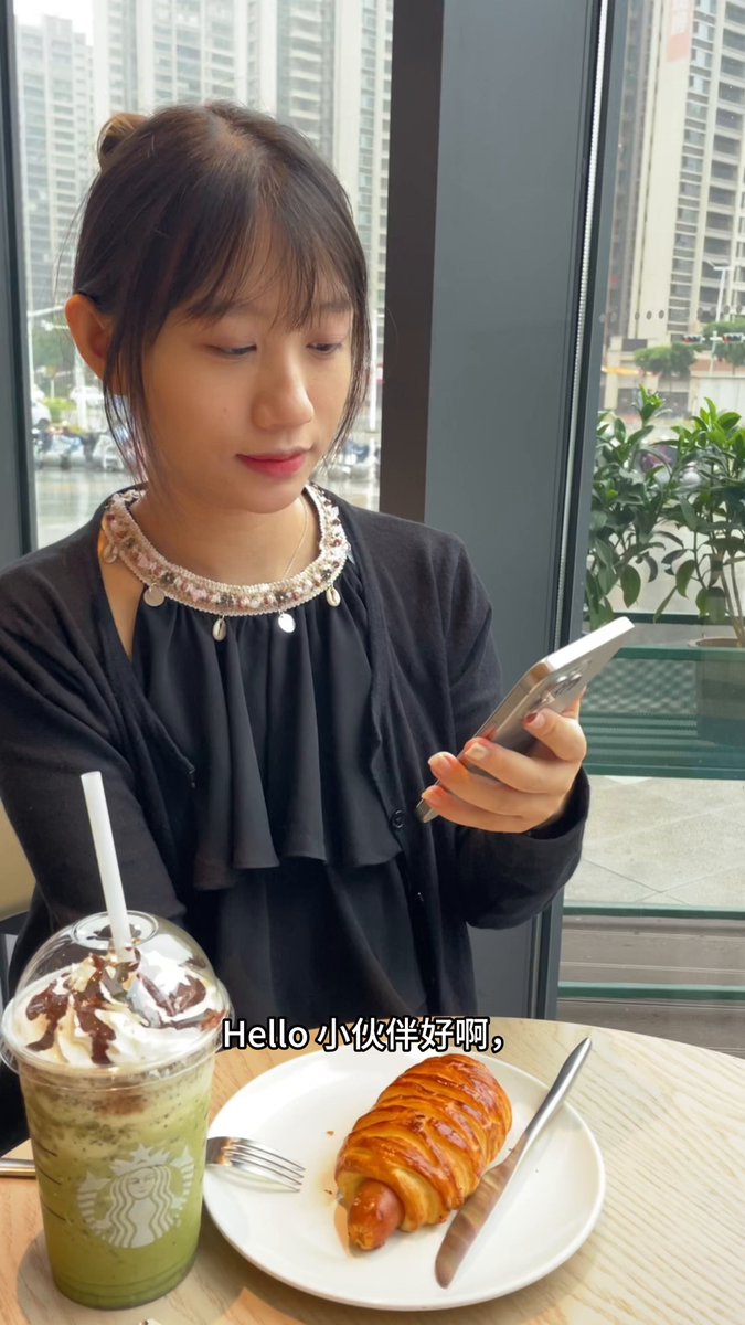 The image features a woman sitting at a table with food, including a croissant and a drink. She is looking down at her cell phone while eating her meal. The photo also includes a watermark that reads "Crypto Survival Plan 15". This suggests that the image might be related to cryptocurrency or digital currency, possibly as part of a promotional campaign for Bitcoin or another cryptocurrency.