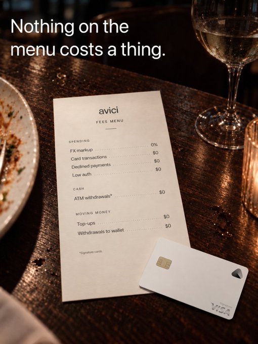 An advertisement for Avici showing a 'Fees Menu' with the tagline 'Nothing on the menu costs a thing,' listing zero-dollar fees for FX markup, card transactions, declined payments, ATM withdrawals, and more, alongside a Visa card on a wooden table.