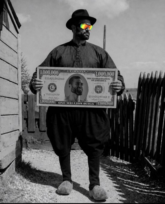 A man wearing a black hat and colorful reflective sunglasses holds a large novelty million-dollar bill featuring his own face, standing outdoors in a black-and-white stylized photo.