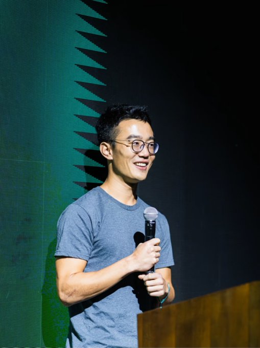 The image shows a smiling young man with glasses holding a microphone, appearing to speak at an event with a green backdrop. The post prompts viewers with a hypothetical question about meeting Jeff Yan, founder of Hyperliquid, inviting them to consider what they would say to him in person—much like the speaker pictured engaging with an audience.