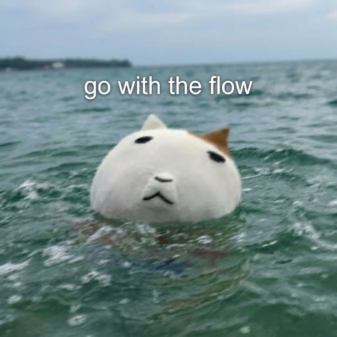 A round white cat face floats in open water with the caption "go with the flow" overlaid. The meme's message of relaxed acceptance and rolling with turbulent conditions humorously parallels the poster's point about $KET holders persevering through multiple crises (suspended accounts, chain migrations, drained wallets) like a cat calmly bobbing through rough seas.