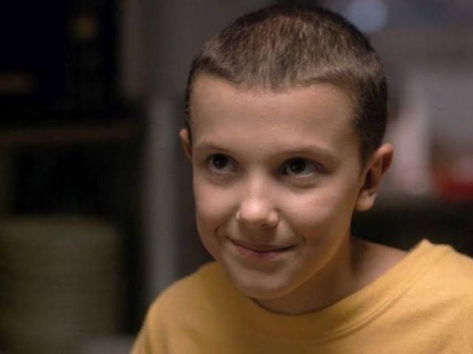 A close-up photo of a young boy with short hair wearing a yellow shirt, smiling subtly.
